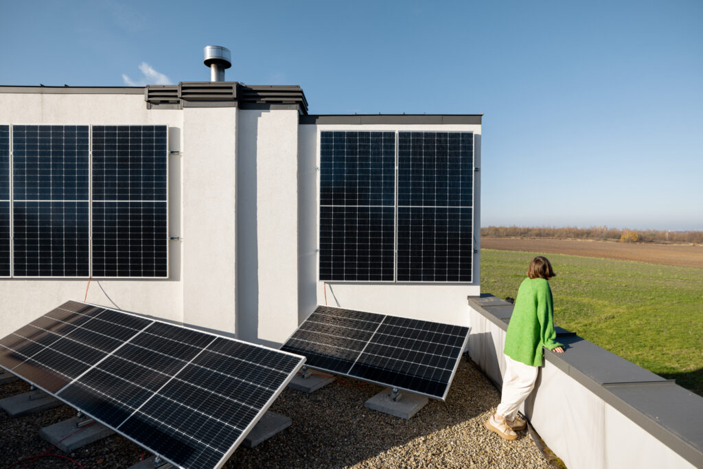 Woman on the rooftop of her house with a solar power plant installed on it. Happy owner of energy-independent household